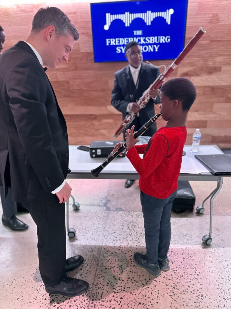 Principal Clarinetist Daniel Kennett shows his instrument to this youngster at the Fiddlestix Instrument Petting Zoo